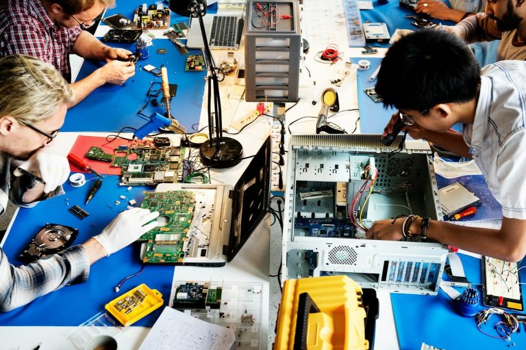 Electronic course People working on electronics and circuit boards at a workshop table.